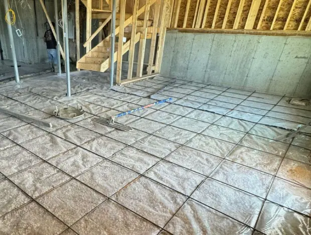 Fresh concrete floor poured in an Edmonton basement with rebar and vapour barrier preparation